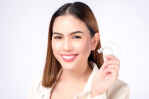 a young doctor holding two invisaligns while Wondering about Does Insurance Cover Invisalign in Rocky Point, NY