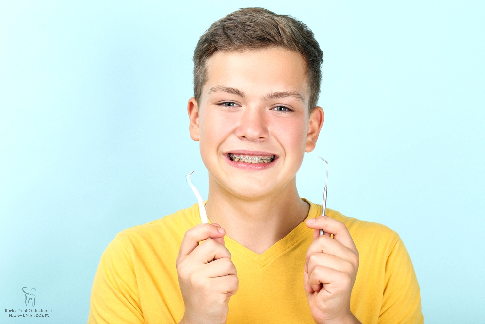 young man with metal braces tootbrush dentist tool - How to Floss with Braces in Rocky Point, NY