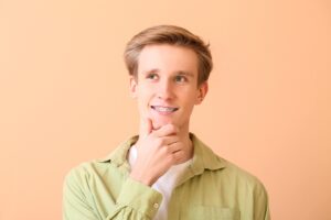 handsome man metal braces color background - How to Get Braces Glue Off Teeth in Rocky Point, NY