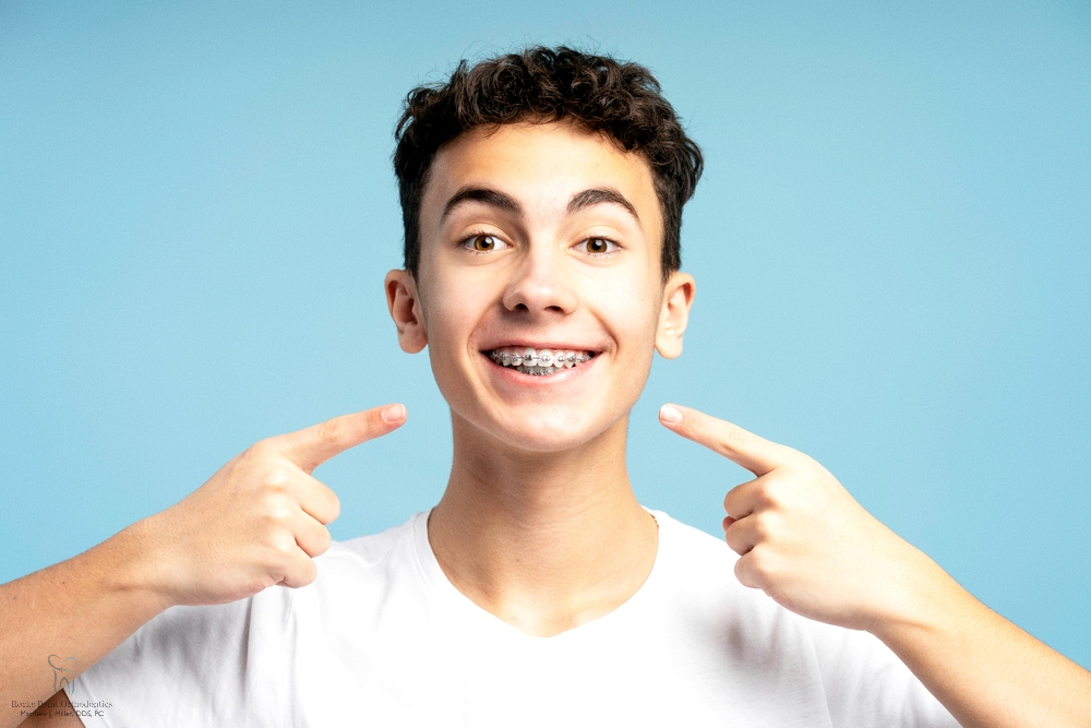 excited smiling boy teenager pointing fingers his metal braces - How to Clean Braces in Rocky Point, NY 