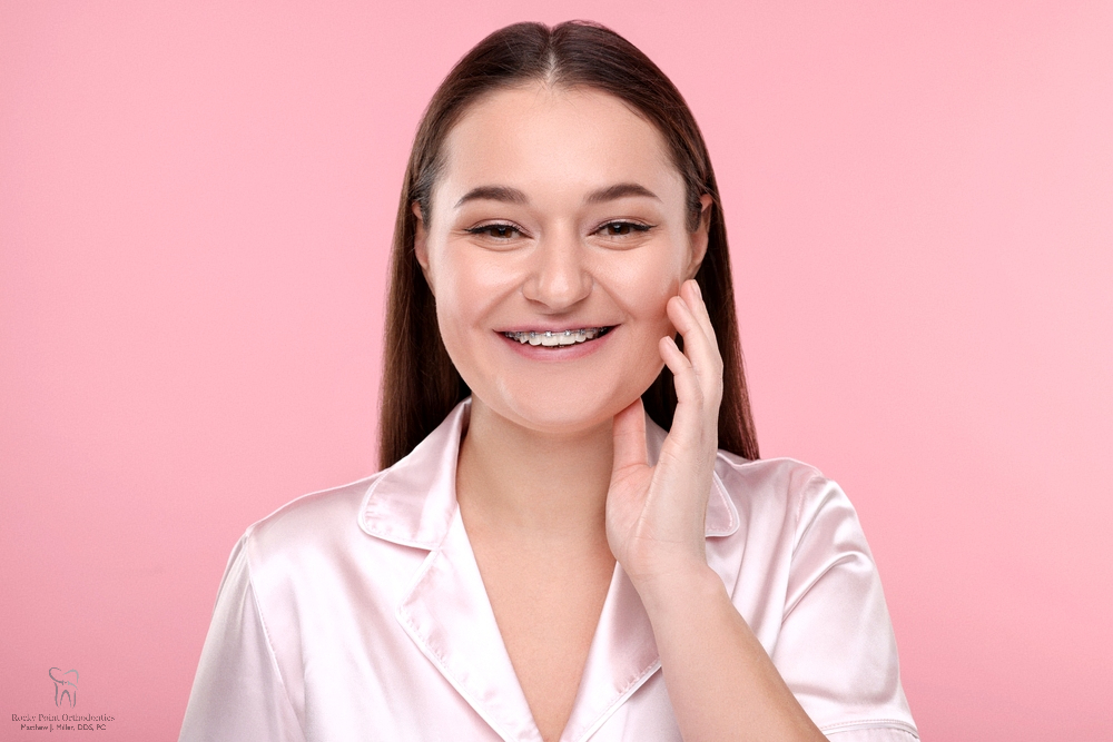 smiling woman dental metal braces pink - How to Clean Braces in Rocky Point, NY 